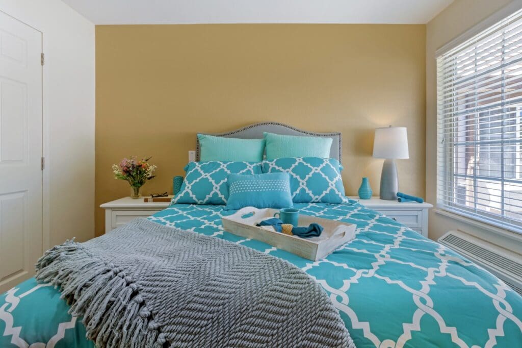 303A2207 Large - Inspirations of Peoria Resident's bedroom with warm colored walls and comfortable looking furniture, with lots of natural light. Inspirations of Peoria senior living.